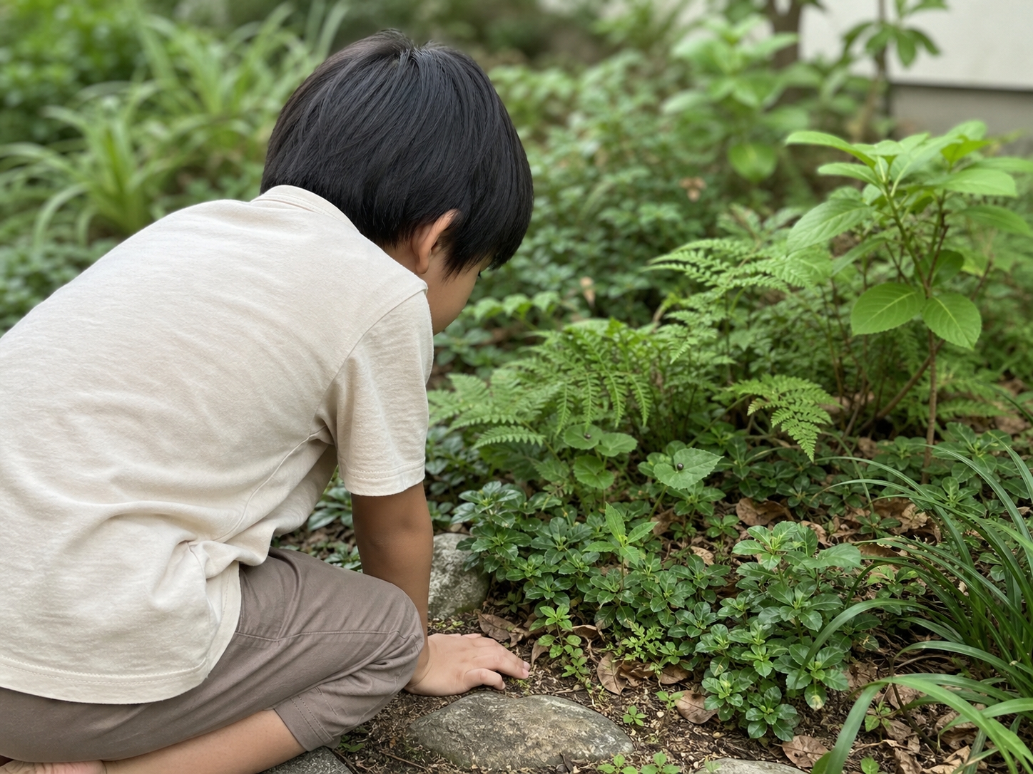 庭の下草をのぞき込む子ども（イメージ・後ろ姿）